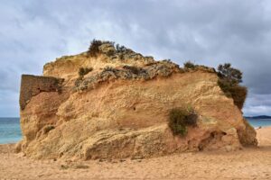 A rugged rock formation on a cloudy day at Algarve beach, Portugal, highlighting natural beauty.
