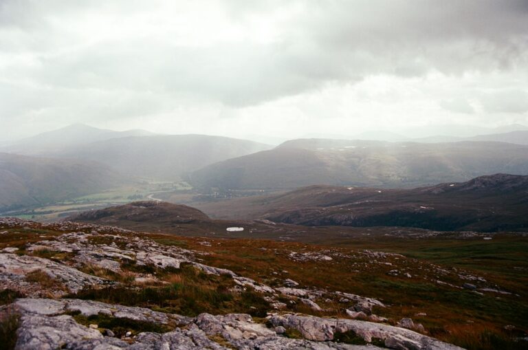 A breathtaking view of the serene Scottish Highlands, showcasing rugged terrain and moody skies.